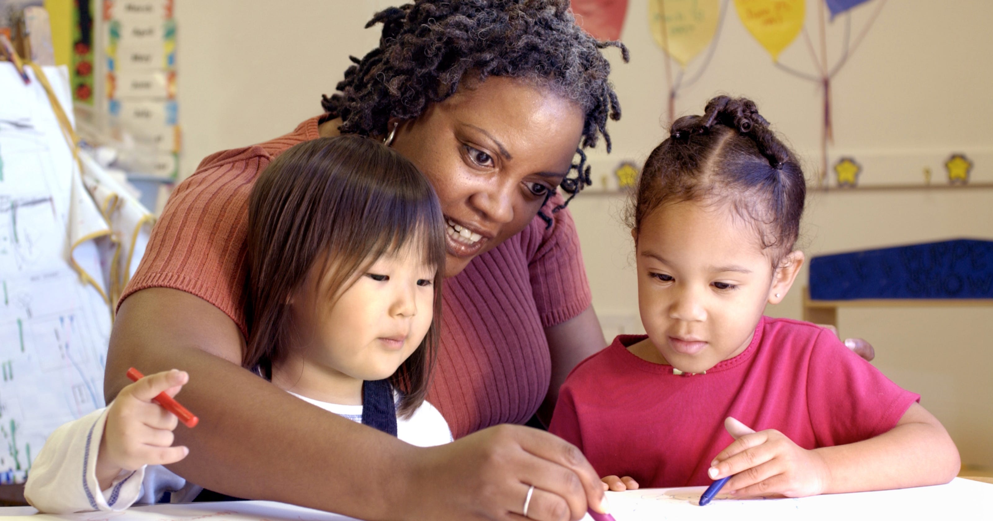 Teacher assisting preschool children with studying